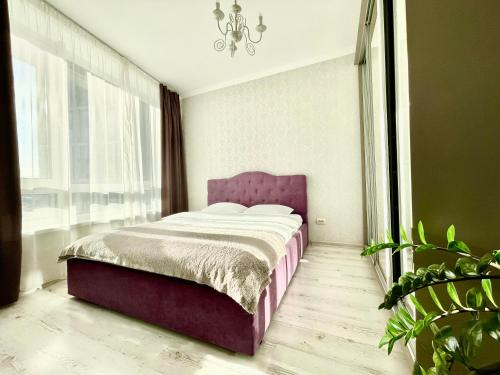 sypialnia z fioletowym łóżkiem i oknem w obiekcie ЖК Славутич апарти w Kijowie