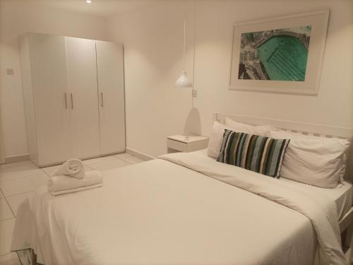een witte slaapkamer met een bed met een handdoek erop bij Luxury Two Bedroom at Embassy Gardens by Morninglife Luxury Apartments in Accra