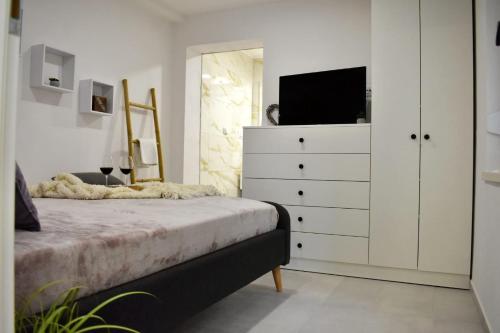 a bedroom with a bed and a dresser with a television at Apartmani Bire in Lumbarda