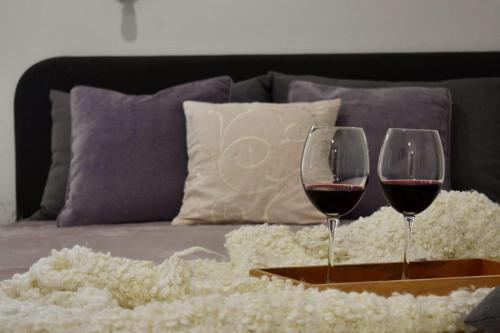 Apartmani Bire في لومباردا: كأسين من النبيذ الأحمر على صينية على أريكة