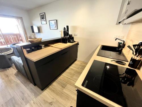 - une cuisine avec un comptoir, un évier et une cuisinière dans l'établissement Résidence Res Cristal - Appartement neuf de charme au pied des pistes MAE-6721, à Notre-Dame-de-Bellecombe