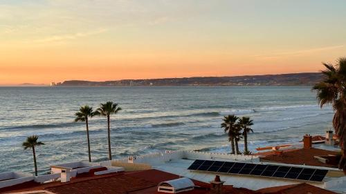 a view of the ocean at sunset with palm trees at Luxury, Ocean View, Pool, Jacuzzi, Valle de Guadalupe, Los Portales De Garcia, Splash, Encanto Restaurants, Surf Breaks in Primo Tapia, Rosarito in Rosarito