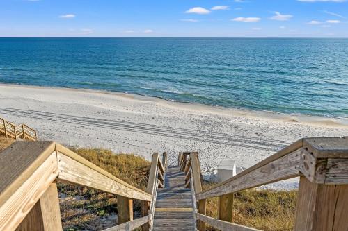 a wooden staircase leading to a beach with the ocean at Sans Souci by 30A Escapes in Seacrest