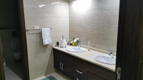 baño con 2 lavabos y espejo grande en Al Andulcia Airport Road Complex مجمع الاندلسية طريق المطار, 