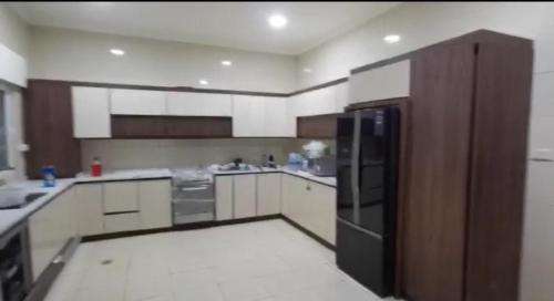 a large kitchen with a black refrigerator in it at Al Andulcia Airport Road Complex مجمع الاندلسية طريق المطار 