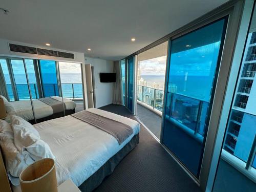 a bedroom with a bed and a balcony with the ocean at Hilton Surfers High Floor Beach Views in Gold Coast