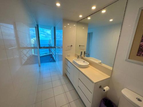 a white bathroom with a sink and a mirror at Hilton Surfers High Floor Beach Views in Gold Coast