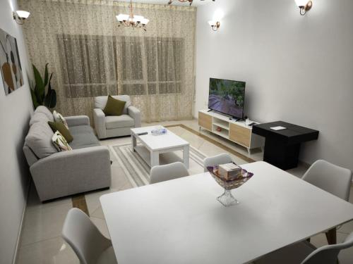 a living room with a white table and a tv at Smart Home Vacation Home in Sharjah