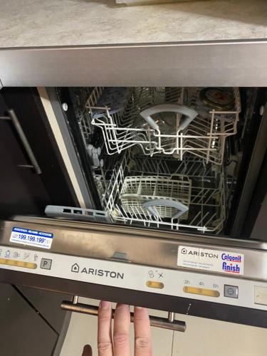 a person reaching into a dishwasher with a dish rack at Elbasan center family apartment n.42 in Elbasan
