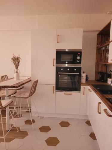 une cuisine avec des armoires blanches, une table et un four dans l'établissement Appartement au cœur de la cité d'Angoulême, à Angoulême