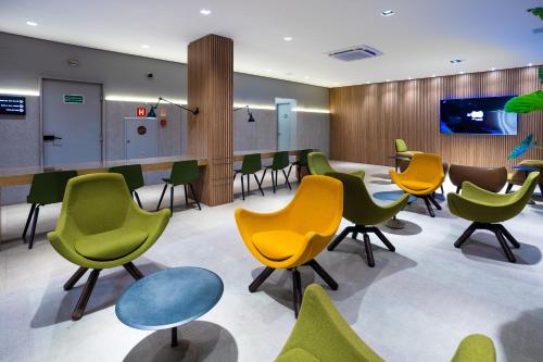 a waiting room with green and yellow chairs at Momax Hotel in Marília