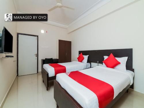 two beds in a hotel room with red pillows at Super Collection O Jagadamba Near Beach Road in Visakhapatnam