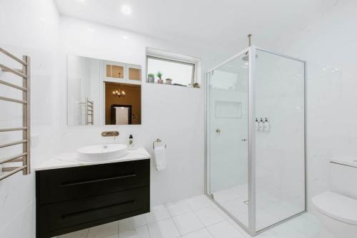 a white bathroom with a sink and a shower at Cawarra on the Park - Historic Mudgee Grandeur in Mudgee