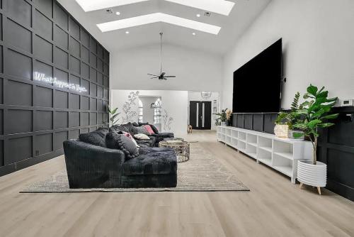 a living room with a black couch and a flat screen tv at 8000sf 7BR Villa Casita Pool Spa Gym & Games in Las Vegas