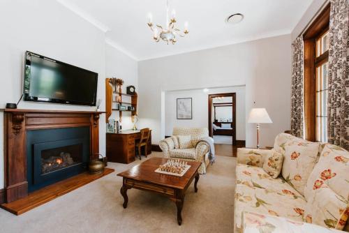 a living room with a fireplace and a tv at Cawarra on the Park - Historic Mudgee Grandeur in Mudgee