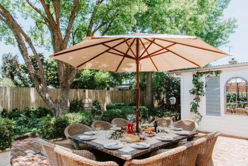 a wooden table with an umbrella in a backyard at Cawarra on the Park - Historic Mudgee Grandeur in Mudgee