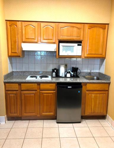 a kitchen with wooden cabinets and a black dishwasher at Country Inn & Suites by Radisson, San Jose International Airport, CA in San Jose
