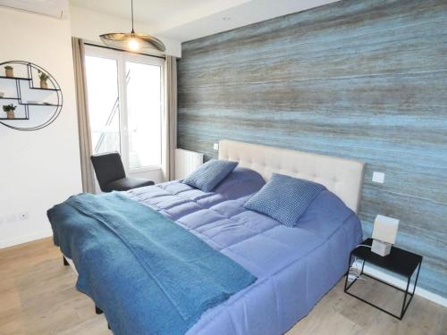 une chambre avec un lit bleu avec un mur en bois dans l'établissement Résidence Le Chateau Durieux 2 - Perle Rare pour ce joli 2 pièces spacieux 4 personnes ! MAE-6504, à Aix-les-Bains