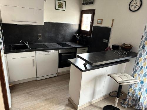 une cuisine avec des armoires blanches et un comptoir noir dans l'établissement Résidence La Baie De Memard - Idéalement situé sur les Bords du Lac d'Aix les Bains ! MAE-6494, à Aix-les-Bains