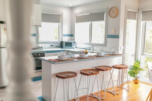 a kitchen with a white island with stools at Ocean Breeze 100m from the Beach, Pet Friendly in Ocean Grove