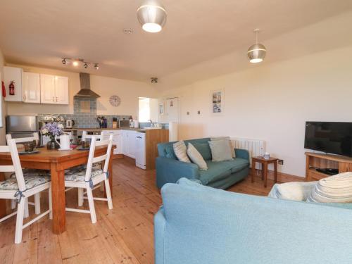 a living room with a blue couch and a table at Kerensa ha-Kres in Sennen