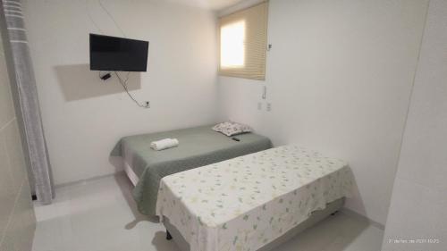Habitación blanca pequeña con 2 camas y TV en Casa mobiliada de 2 suítes na R São Lázaro 2367 - 2370 - Jardim Gonzaga en Juazeiro do Norte