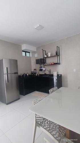 uma cozinha com um frigorífico de aço inoxidável e uma mesa em Casa mobiliada de 2 suítes na R São Lázaro 2367 - 2370 - Jardim Gonzaga em Juazeiro do Norte