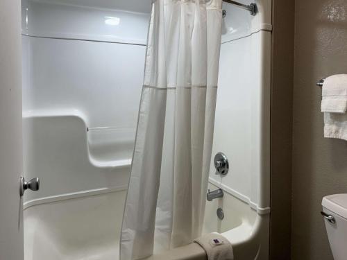 a shower with a white shower curtain in a bathroom at Motel 6-Bradenton, FL in Bradenton