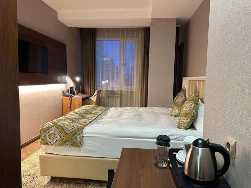 a hotel room with a bed with a table and a window at Best Western Plus Astana Hotel in Astana