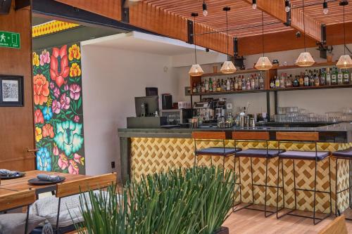 een restaurant met een bar met een muurschildering van bloemen bij Casa de la Luz Hotel Boutique in Mexico-Stad