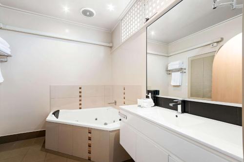 a bathroom with a tub and a sink and a mirror at Comfort Inn & Suites Lakes Entrance in Lakes Entrance