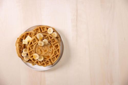 a bowl of waffles with bananas on a table at Pear Tree Inn Cape Girardeau Medical Center in Cape Girardeau
