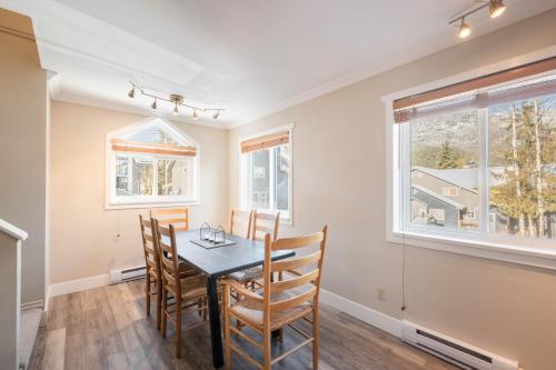 a dining room with a table and chairs and windows at Gondola Heights by Outpost Whistler in Whistler