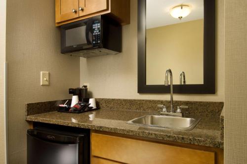 a kitchen with a sink and a microwave at Drury Plaza Hotel San Antonio North Stone Oak in San Antonio