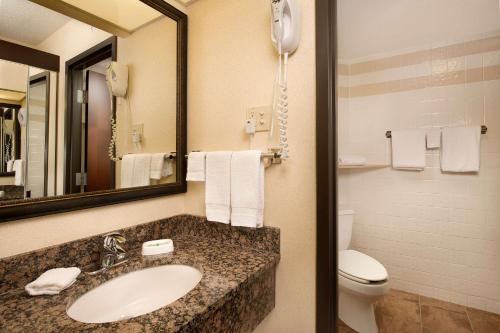 ein Badezimmer mit einem Waschbecken, einem WC und einem Spiegel in der Unterkunft Drury Inn & Suites Springfield in Springfield