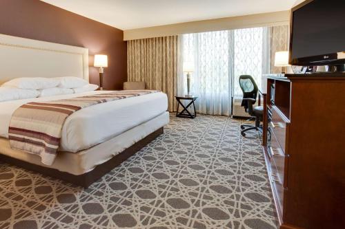 a hotel room with a bed and a flat screen tv at Drury Inn & Suites Louisville East in Louisville