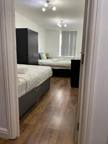 1 dormitorio con 2 camas y suelo de madera en Rusholme Rooms en Mánchester