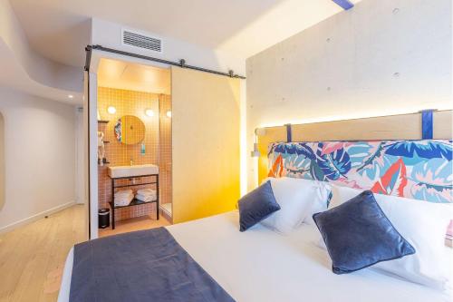 a bedroom with a large white bed with blue pillows at Urban Hotel & Spa Aix-les-Bains - BW Signature Collection in Aix-les-Bains