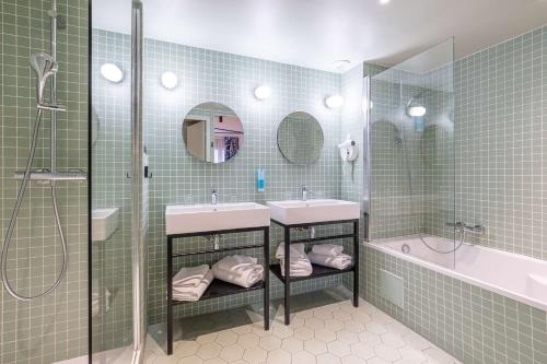 a bathroom with two sinks and a shower and a tub at Urban Hotel & Spa Aix-les-Bains - BW Signature Collection in Aix-les-Bains