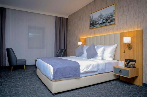 a hotel room with a large bed and a chair at Best Western Premier DJ Hotel in Djibouti