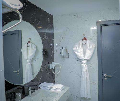 ein Bad mit einem Spiegel und einem Bademantel an der Wand in der Unterkunft Best Western Premier DJ Hotel in Dschibuti
