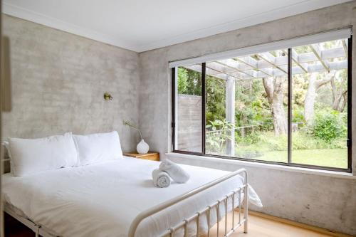 a bedroom with a bed and a large window at Narrawallee Beach House in Narrawallee