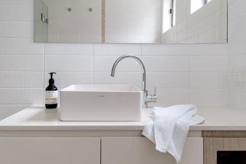 a white sink with a bottle of wine on a counter at Narrawallee Beach House in Narrawallee