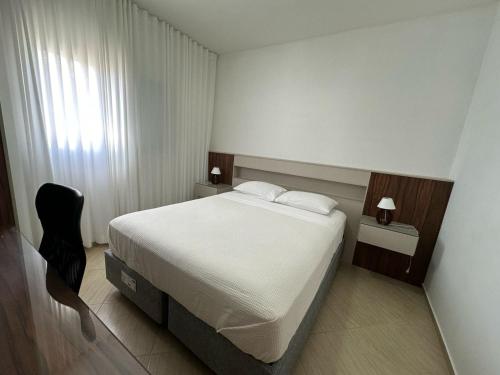 sypialnia z białym łóżkiem i czarnym krzesłem w obiekcie Residencial 04 Monte Carlo em São Roque w mieście São Roque