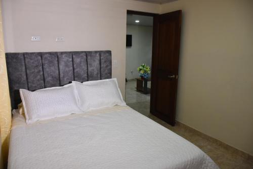 um quarto com uma cama grande e almofadas brancas em Confortable apartamento cerca de la plaza principal em Villa de Leyva
