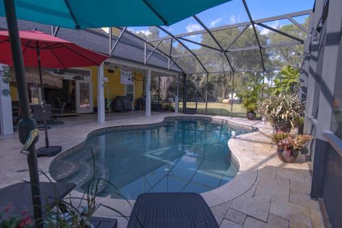 a swimming pool with an umbrella next to a building at Paradise in a country setting 1100 sq ft apartment in Lake Mary