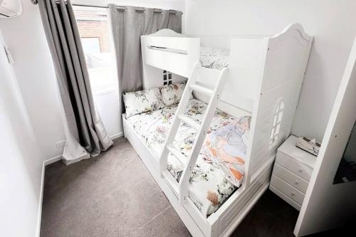 a white bunk bed with a ladder in a room at Fully renovated 3 bedroom house & Free Parking in Gold Coast