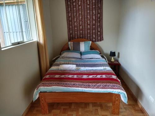 een klein bed in een kamer met een raam bij Casa con jardín y vista a las montañas Pisac in Pisac