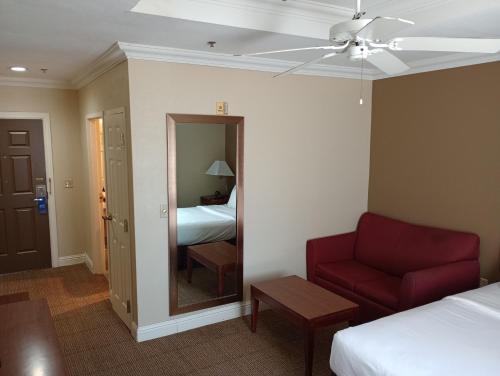 a hotel room with a red couch and a mirror at SAMIR Stay at NW Expressway in Oklahoma City