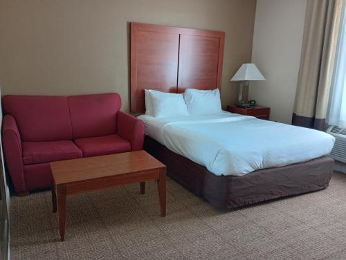 a hotel room with a bed and a red couch at SAMIR Stay at NW Expressway in Oklahoma City